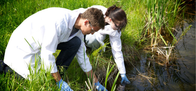 two young researchers collecting water specimen from a field