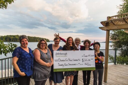 seven woman at a deck holding a novelty cheque
