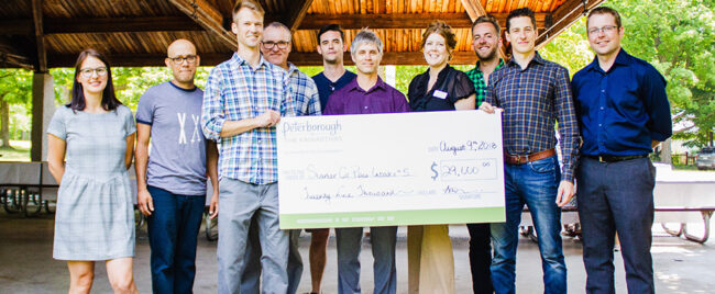 A group of people carrying a novelty cheque