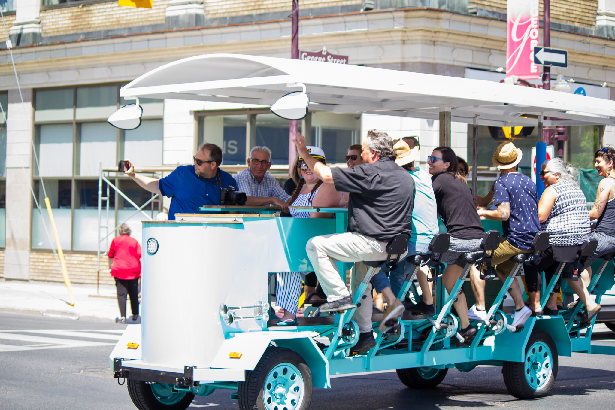 people waving while pedaling a very large bike