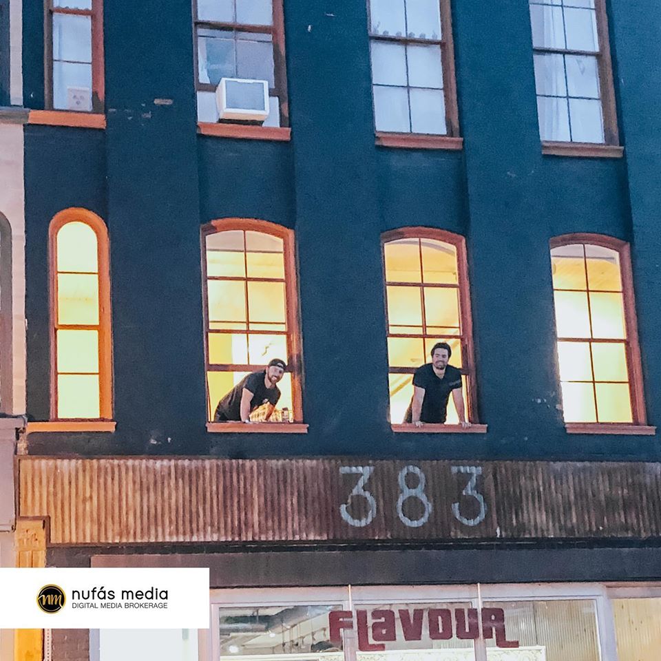 two men looking through the windows of a building reading the number '383'