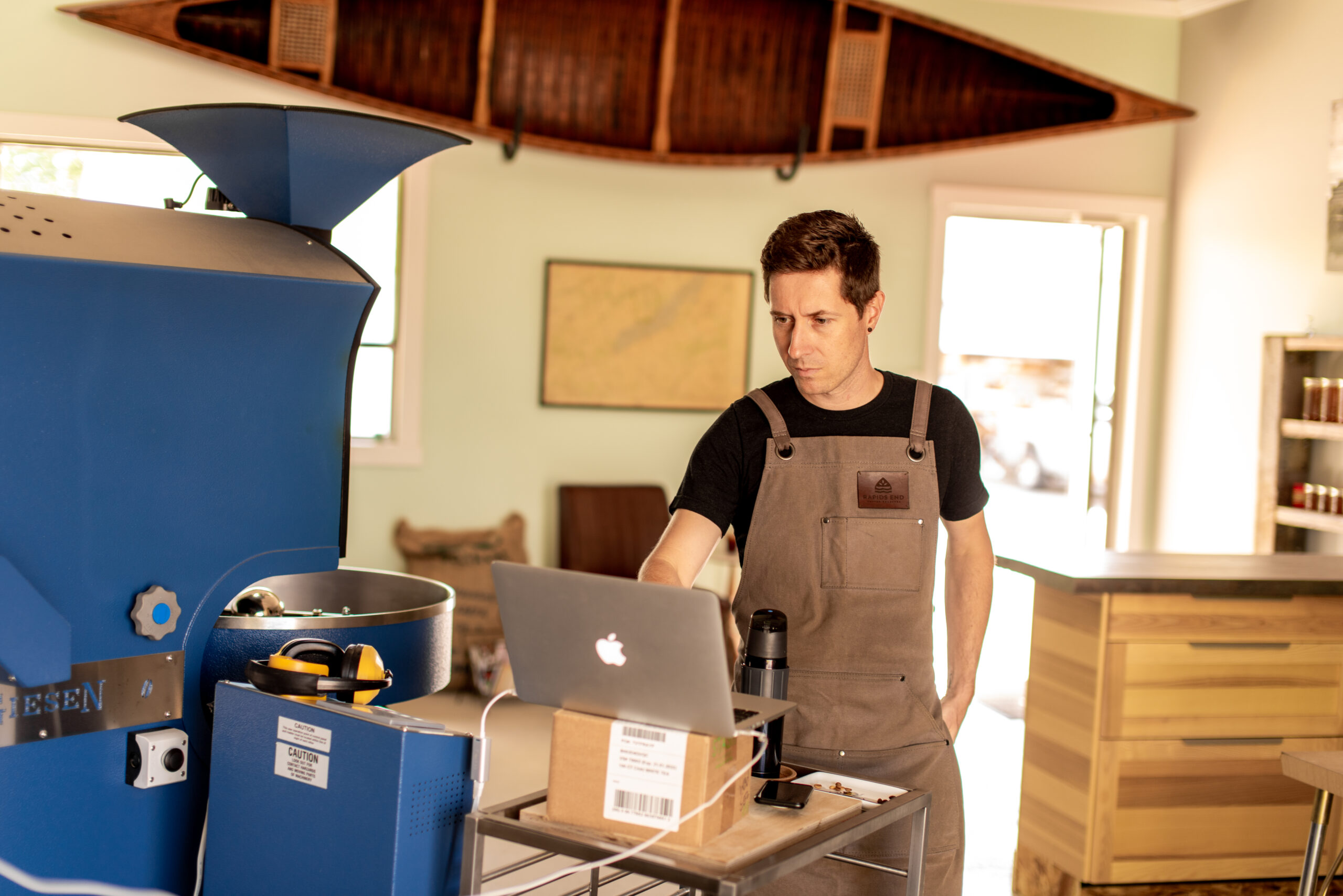 Daniel Biro working on a laptop in front of big coffee machine