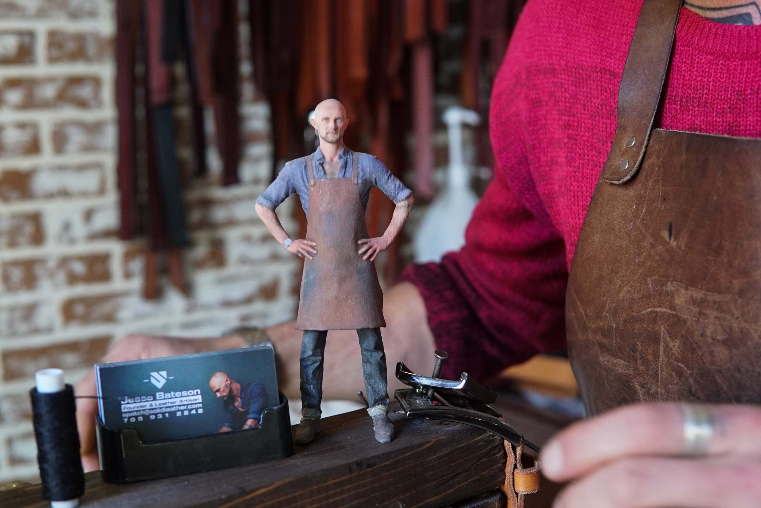 a human miniature figurine wearing leather apron and with visiting cards kept aside