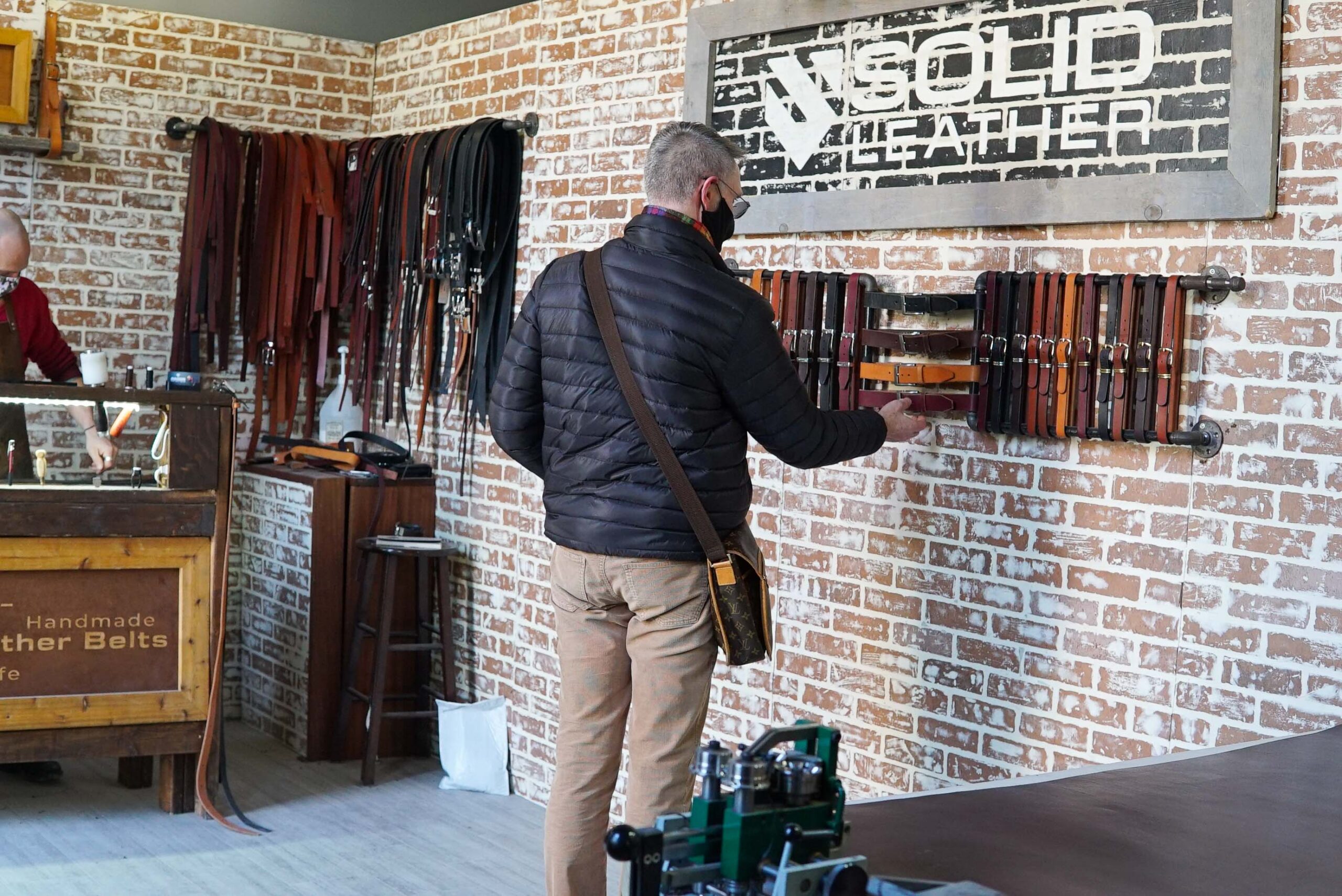 a customer touching leather belts on display in the Solid Leather shop
