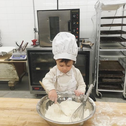 child dressed as chef playing with dough
