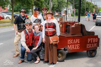 six people in period costumes with a historic vehicle