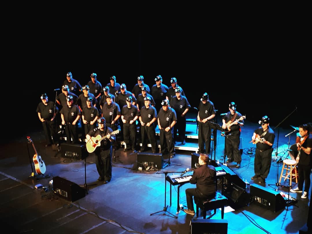 musicians in black clothes performing on stage