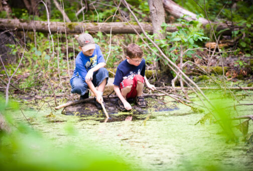 Two boys playing by a swamp