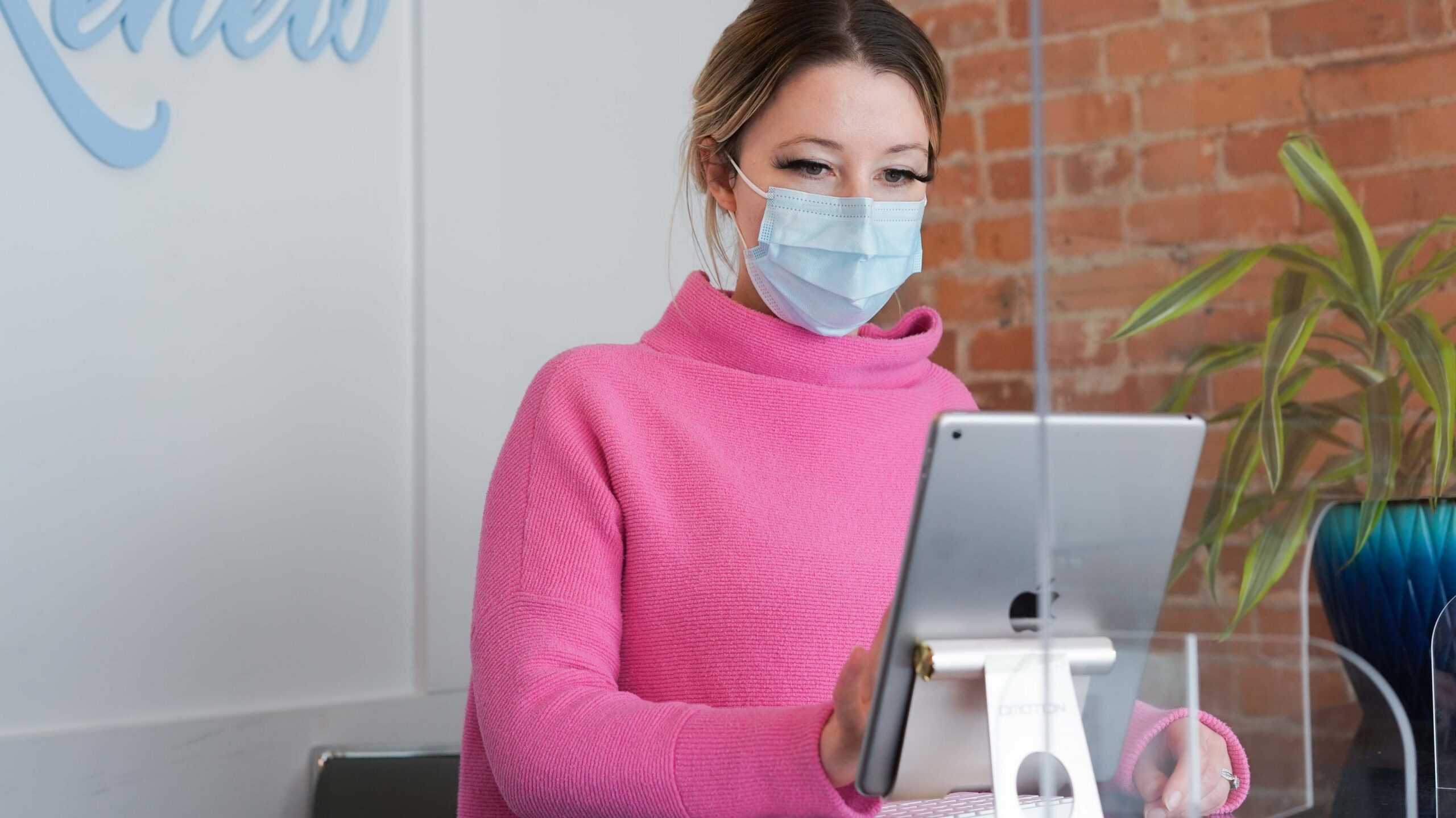 a masked woman working on iPad