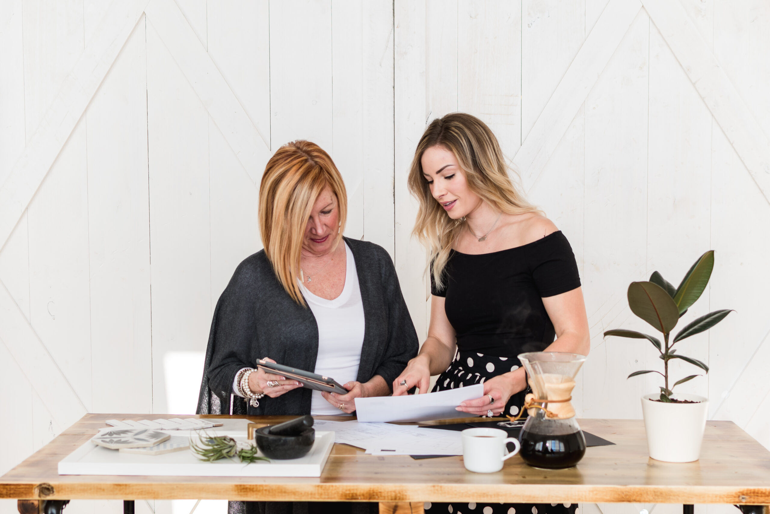 two women discussing paperwork on table