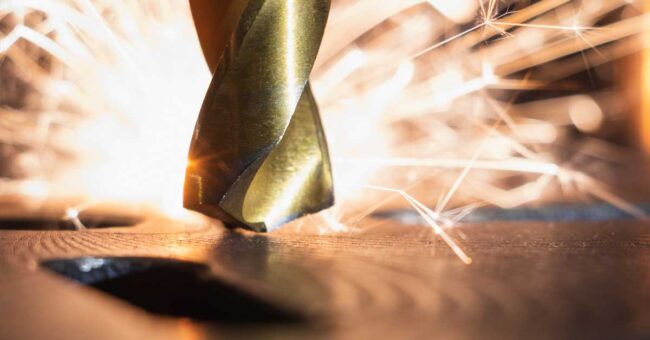 Close up view of a drill bit with sparks in the background