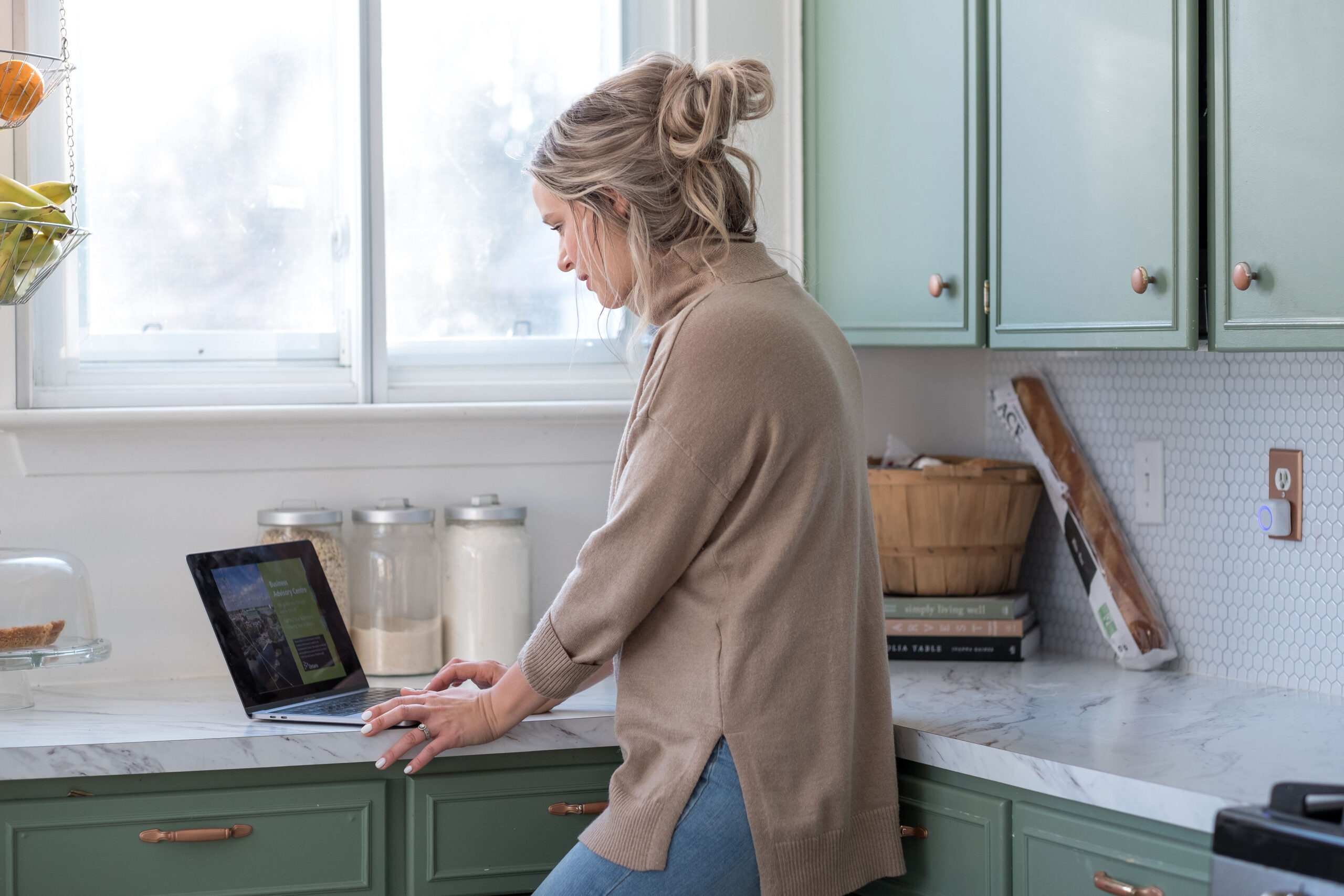 woman standing & working on her laptop kept on kitchen counter