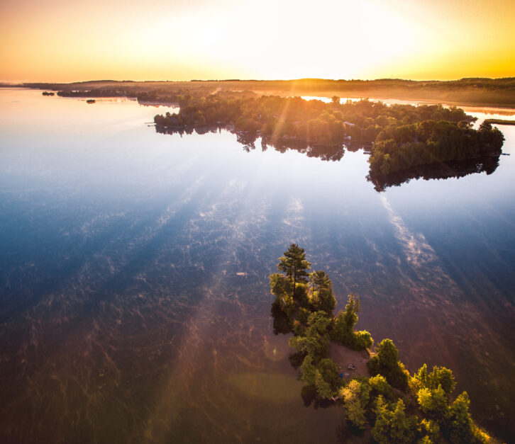 aerial view of lake and trees at sunset