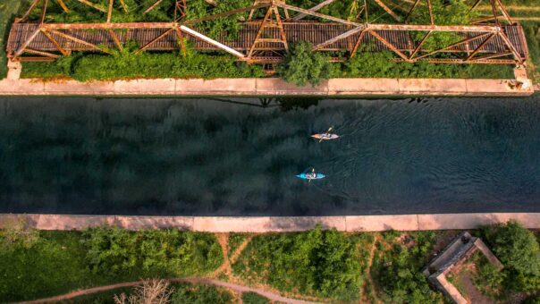 An aerial view of two people kayaking on a narrow waterway