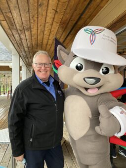 picture of man standing with 55 plus summer games mascot pachi