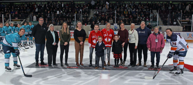 photo of group of people standing on ice surface at arena for ceremonial puck drop