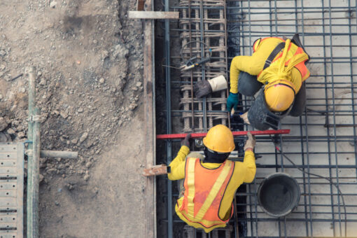 Two people with construction gear work with rebar