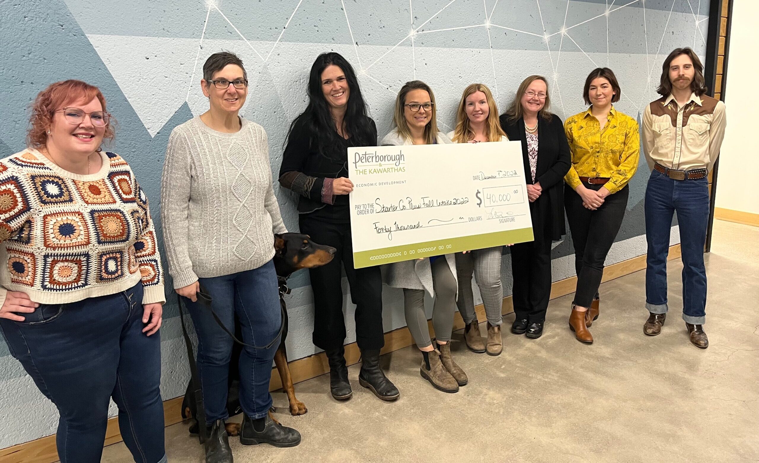 Eight business owners standing in a line holding a giant starter Company Plus cheque . (L-R, Vanessa Bruce, Ineke Turner, Lisa Mace, Jena Trimble, Kate Griffin, Lisa Burkitt, Jacquelyn Craft, Nathan Truax)