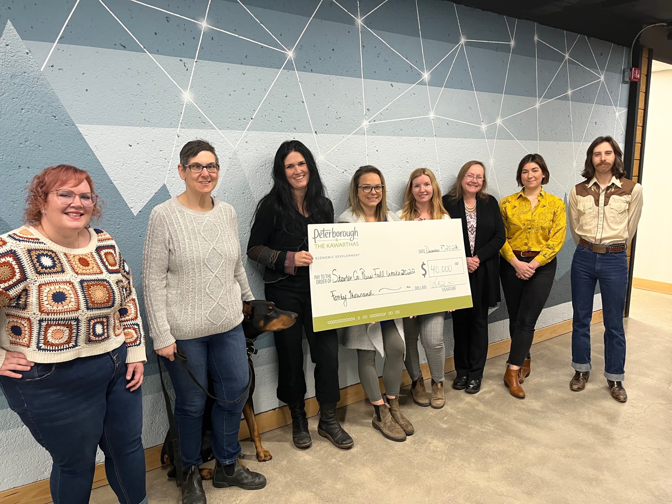Eight business owners standing in a line holding a giant starter Company Plus cheque . (L-R, Vanessa Bruce, Ineke Turner, Lisa Mace, Jena Trimble, Kate Griffin, Lisa Burkitt, Jacquelyn Craft, Nathan Truax)