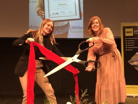 Ella Fischer-Slack (left) and Madeleine Hurrell (right) cutting a red ribbon with giant scissors