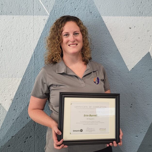Erin Burrell standing in front of a geometric background holding a Starter Company Plus certificate