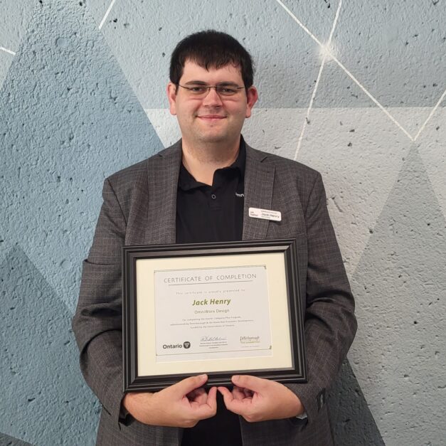 Jack Henry standing in front of a geometric background holding a Starter Company Plus certificate