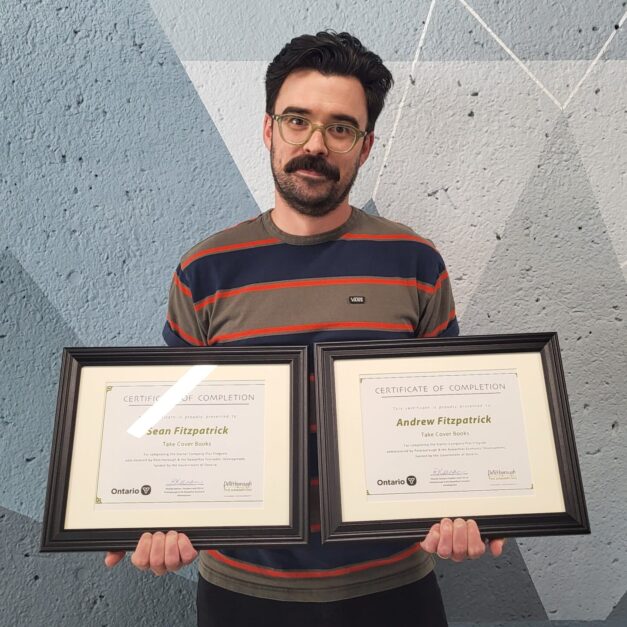 Andrew Fitzpatrick standing in front of a geometric background holding a Starter Company Plus certificate