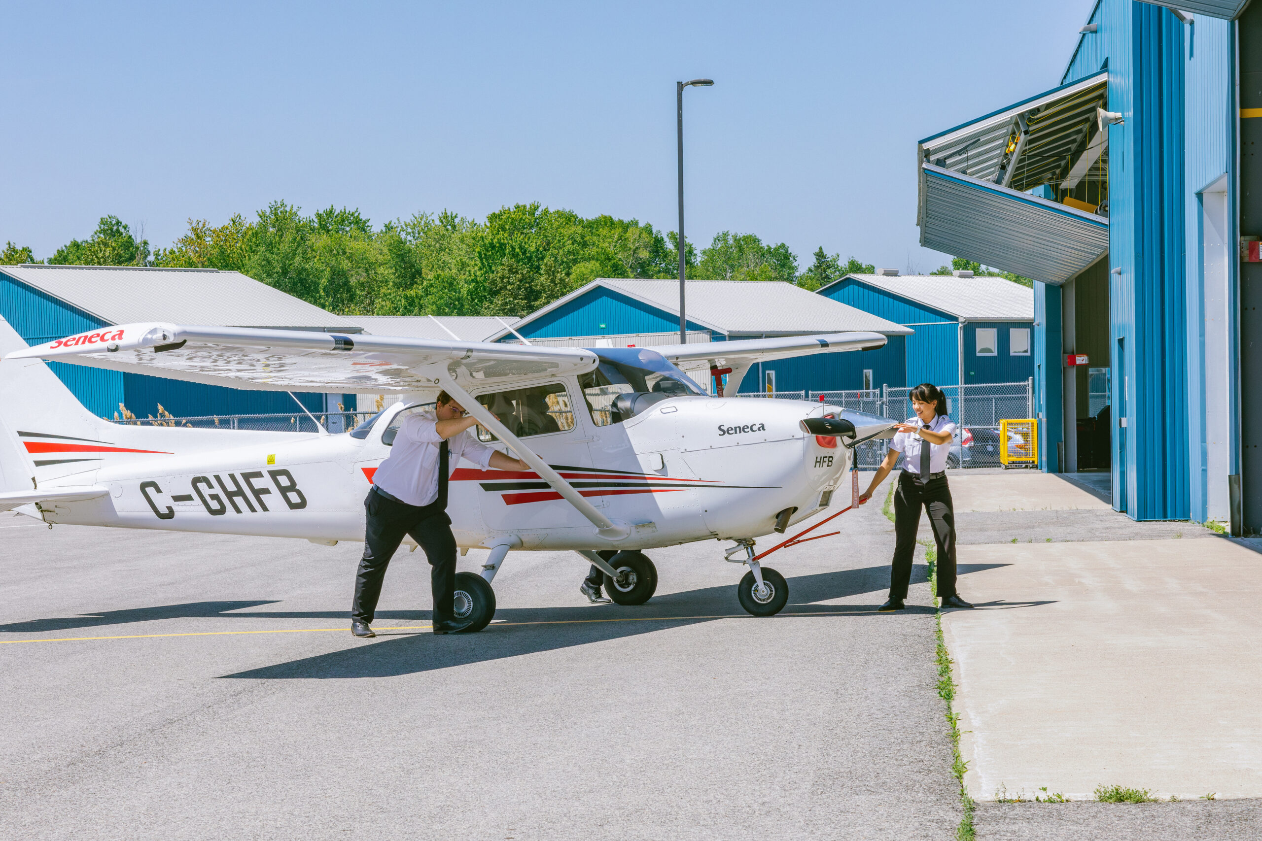 Two people guiding a small plane into a hanger