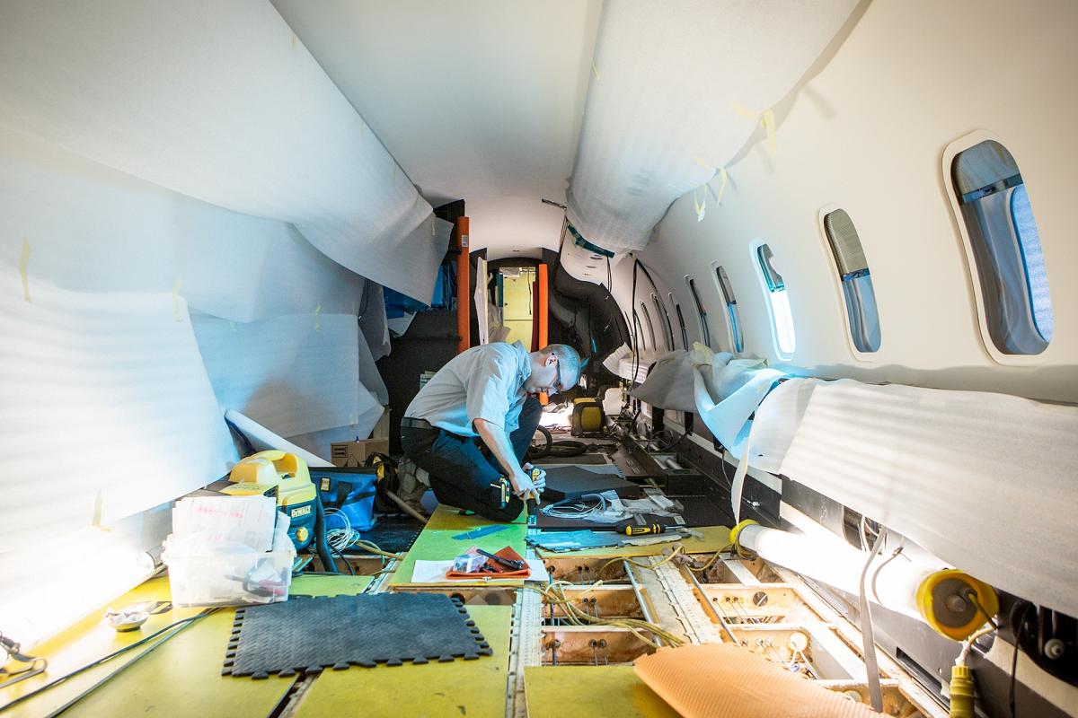 Man kneeling and working on the interior of an airplane